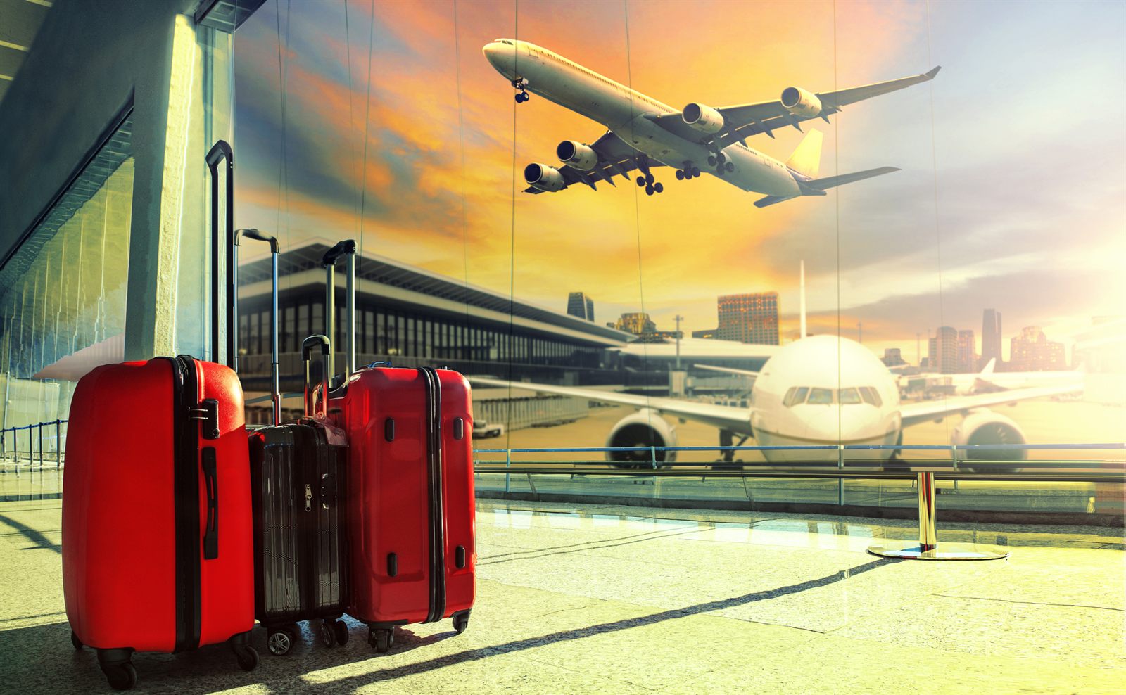 Red suitcases on an airport apron with an airliner overhead