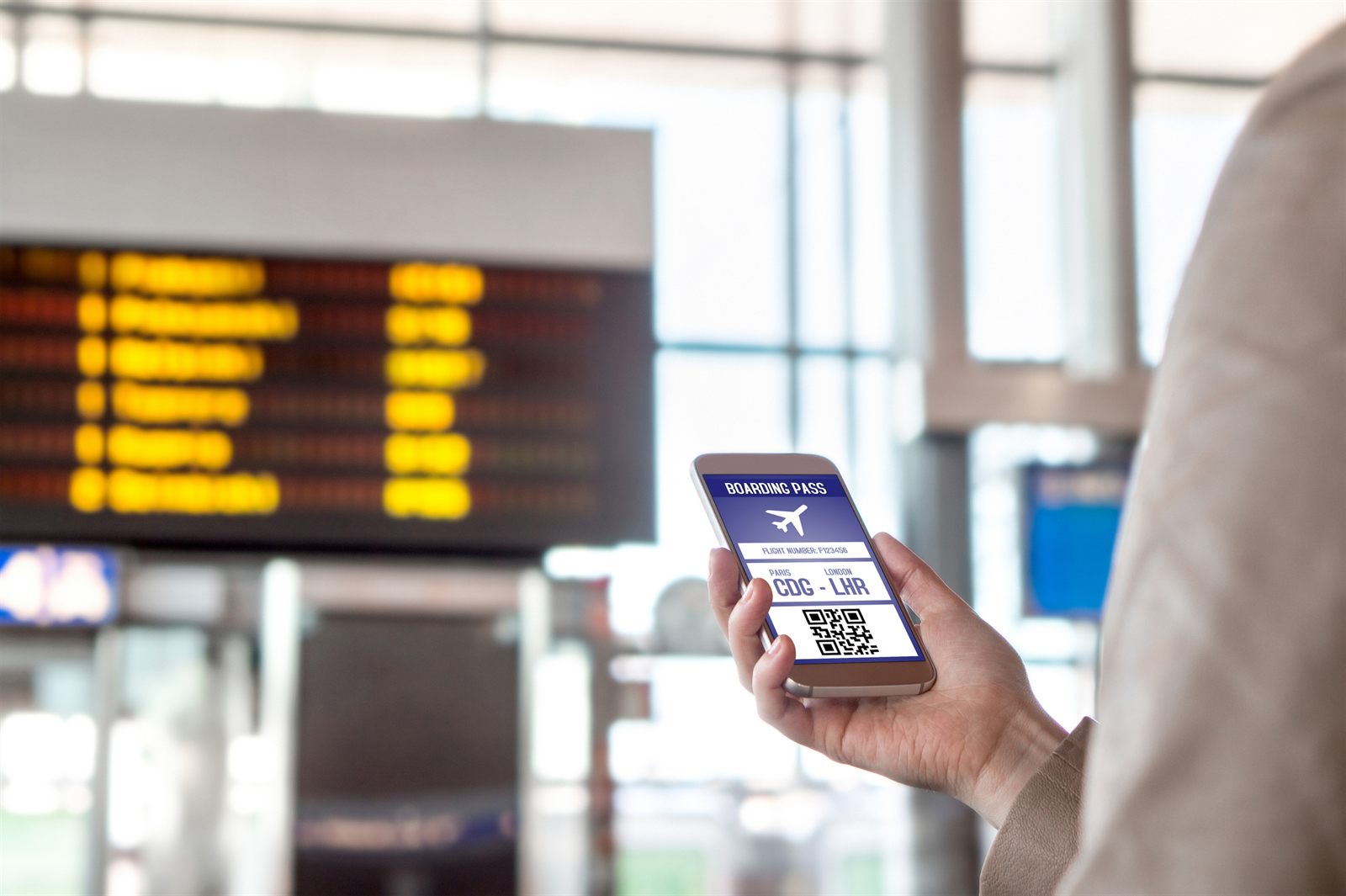 Traveler checking a phone in front of a departures board