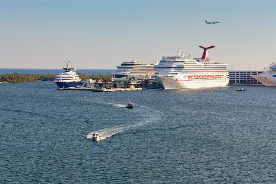 Cruise ships at a port with a jet passing overhead