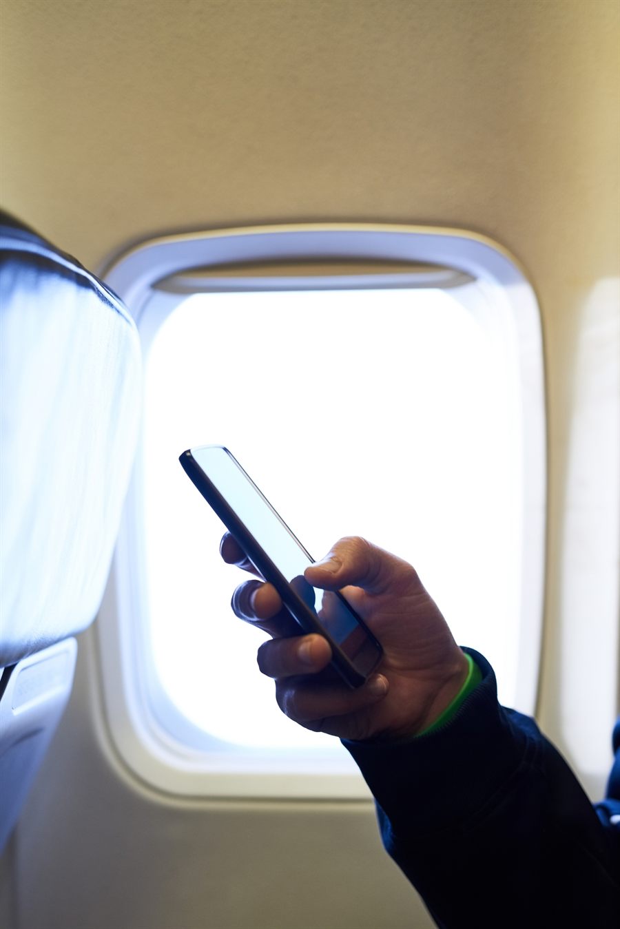 Passenger holding a phone beside an airplane window